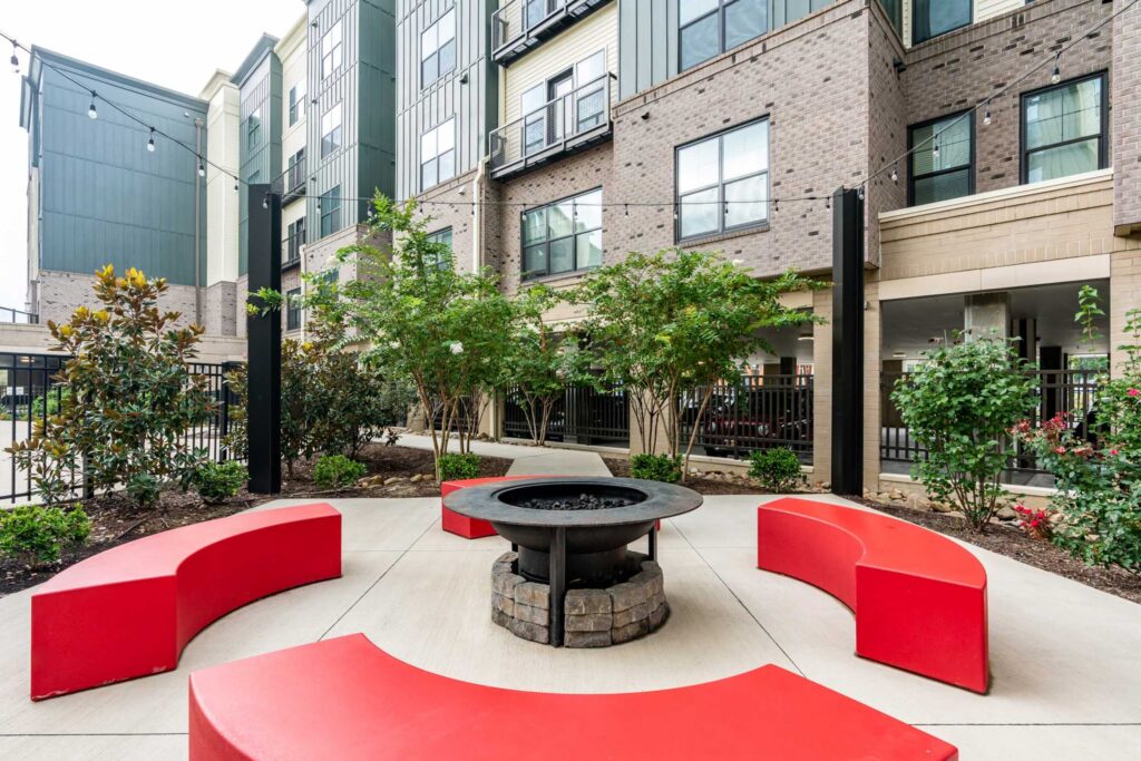 Outdoor courtyard outside apartments with firepit and red benches