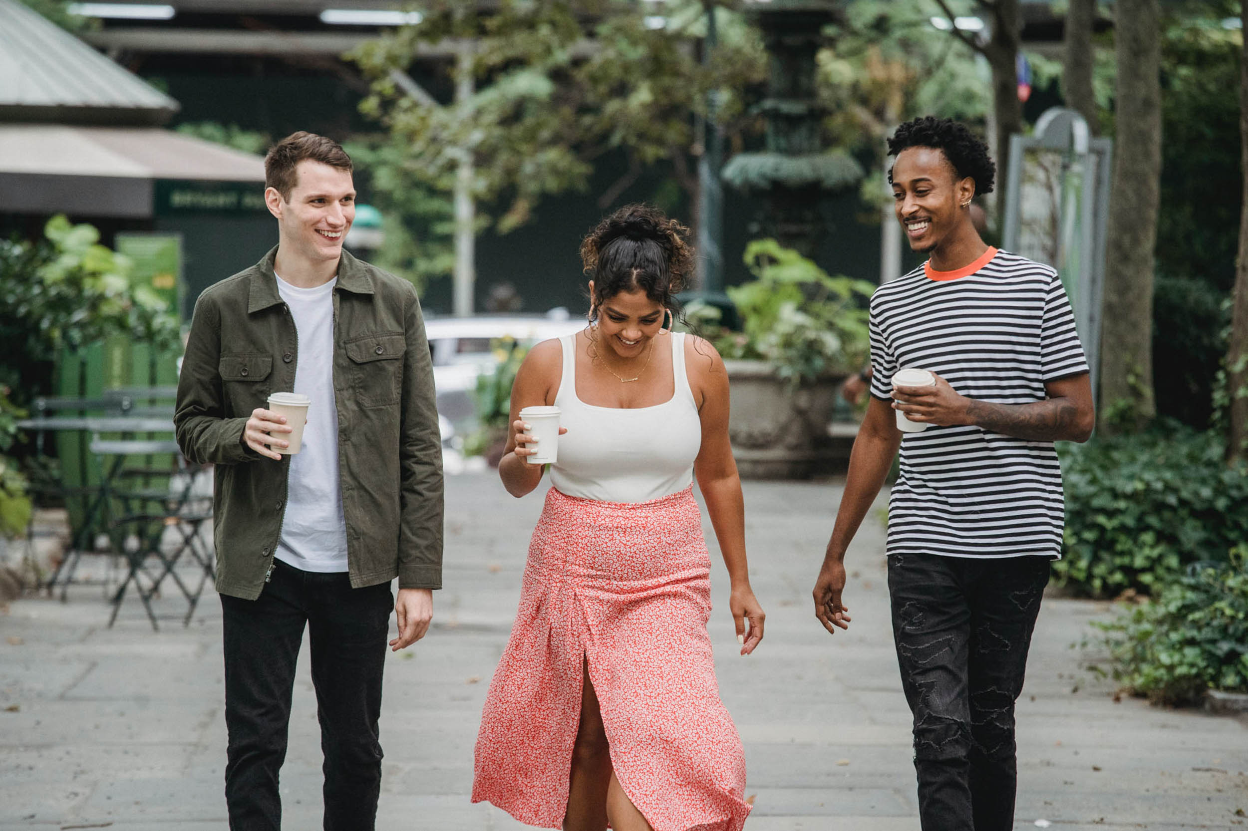 Three friends walking down sidewalk with takeout coffees